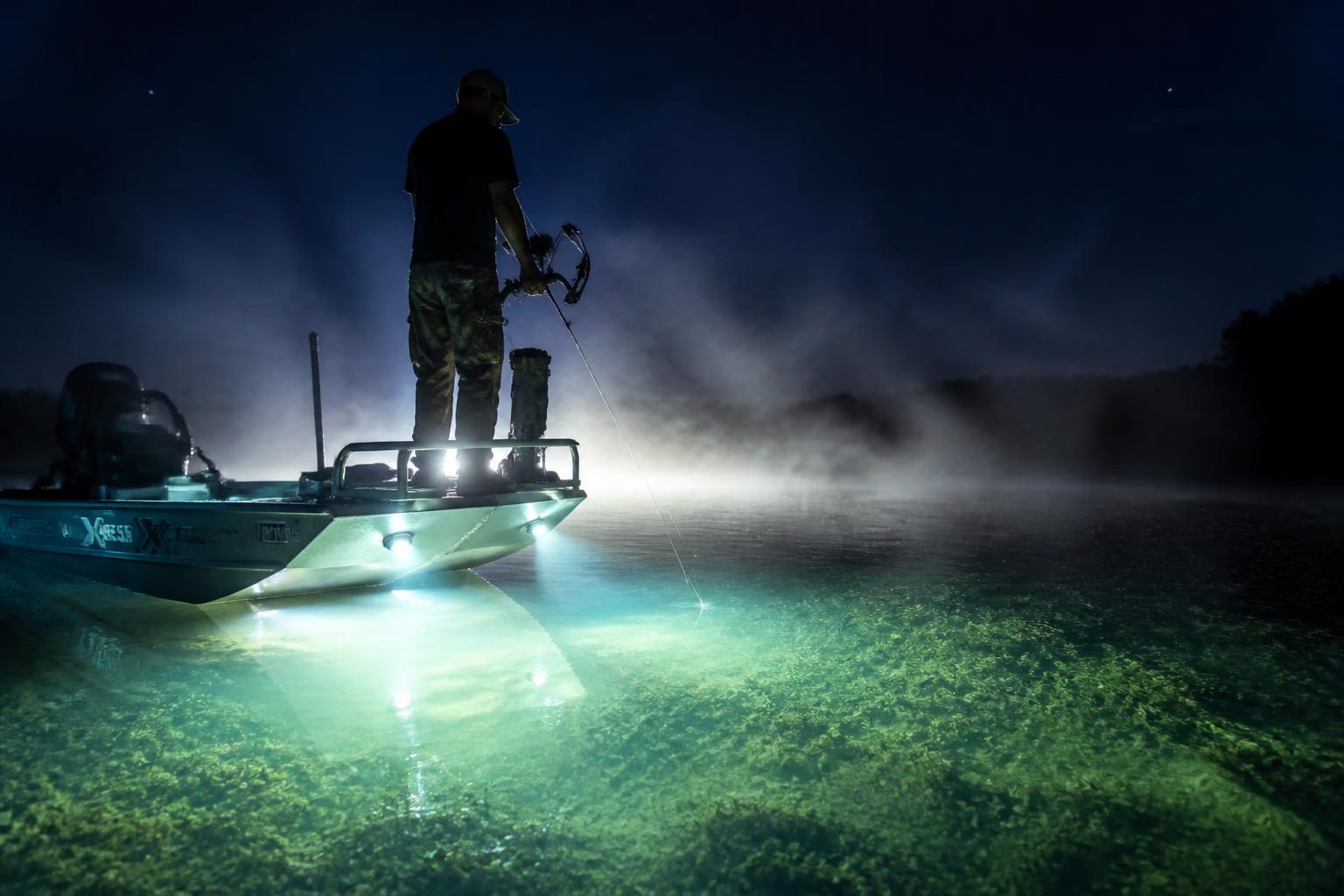 Bowfishing at night from a light-rigged boat over clear shallow water